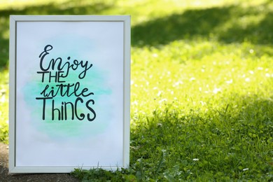 Photo of Poster with phrase Enjoy The Little Things on grass outdoors, space for text