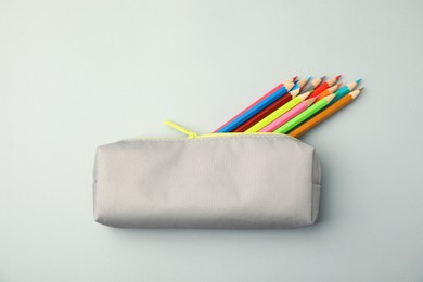 Photo of Many colorful pencils in pencil case on light grey background, top view