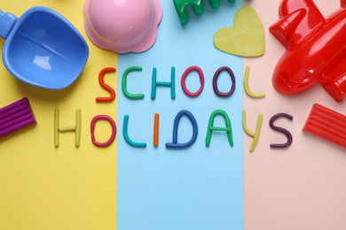 Photo of Flat lay composition with phrase School Holidays made of modeling clay on color background