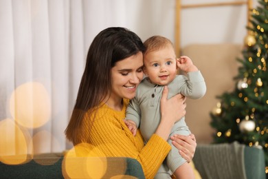 Happy young mother with her cute baby in room decorated for Christmas. Winter holiday