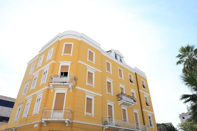 Photo of Beautiful yellow building with balconies outdoors, low angle view