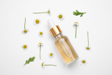Photo of Composition with chamomile flowers and bottle of essential oil on white background, top view
