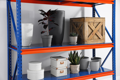 Photo of Metal shelving unit with different household stuff on light background
