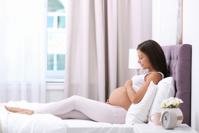 Photo of Happy pregnant woman lying on bed at home