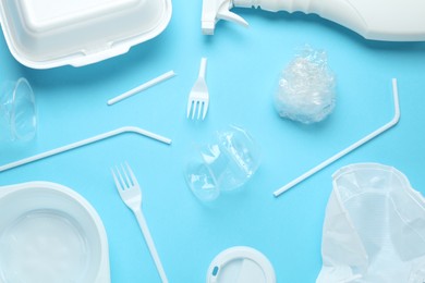 Photo of Different plastic items on light blue background, flat lay