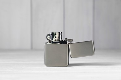 Photo of Gray metallic cigarette lighter on white wooden table