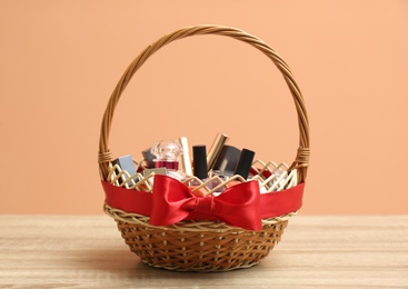 Photo of Wicker gift basket with cosmetic products on wooden table