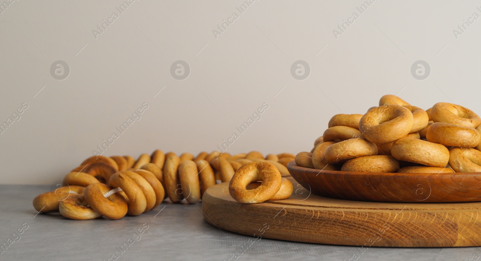 Photo of Plate with delicious ring shaped Sushki (dry bagels) on light grey table. Space for text