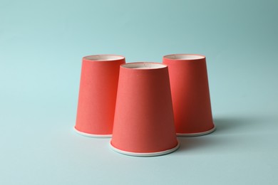 Three red cups on light blue background. Thimblerig game