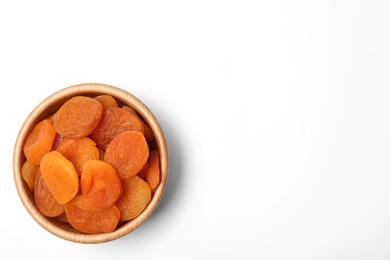 Photo of Wooden bowl of dried apricots on white background, top view with space for text. Healthy fruit