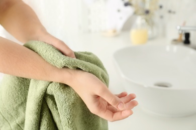 Photo of Woman wiping hands with towel in bathroom, closeup