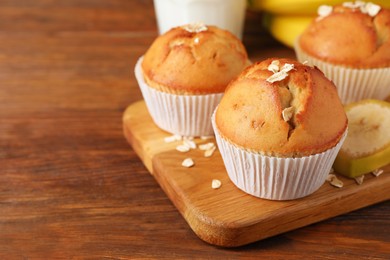 Photo of Tasty muffins served with banana on wooden table. Space for text