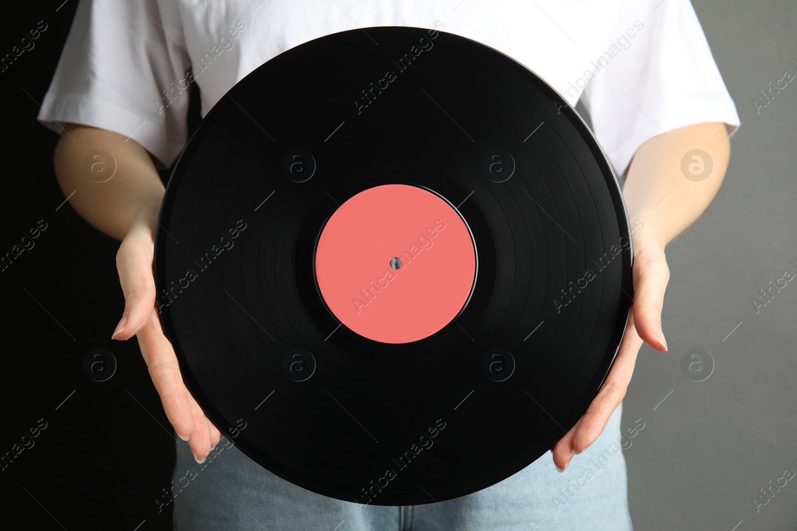 Photo of Woman holding vintage vinyl record on grey background, closeup