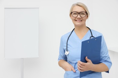 Photo of Professional doctor wearing uniform near flipchart in clinic, space for text