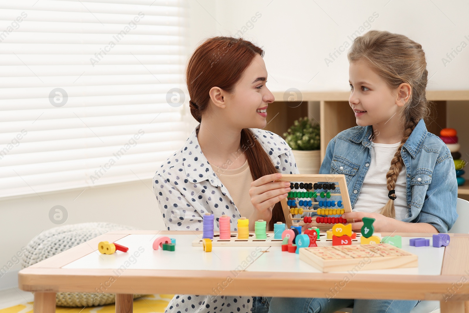 Photo of Happy mother and daughter playing with abacus at desk in room. Learning mathematics with fun