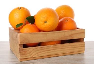 Fresh oranges in crate on light wooden table against white background