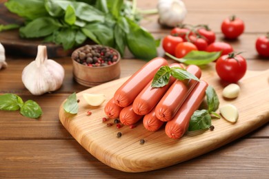 Photo of Fresh raw vegetarian sausage with basil and vegetables on wooden table