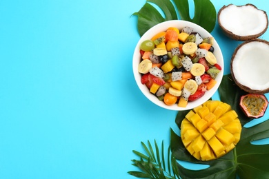 Photo of Flat lay composition with delicious exotic fruit salad on light blue background. Space for text