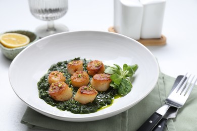 Photo of Delicious fried scallops with tasty sauce and corn salad in bowl on white table, closeup