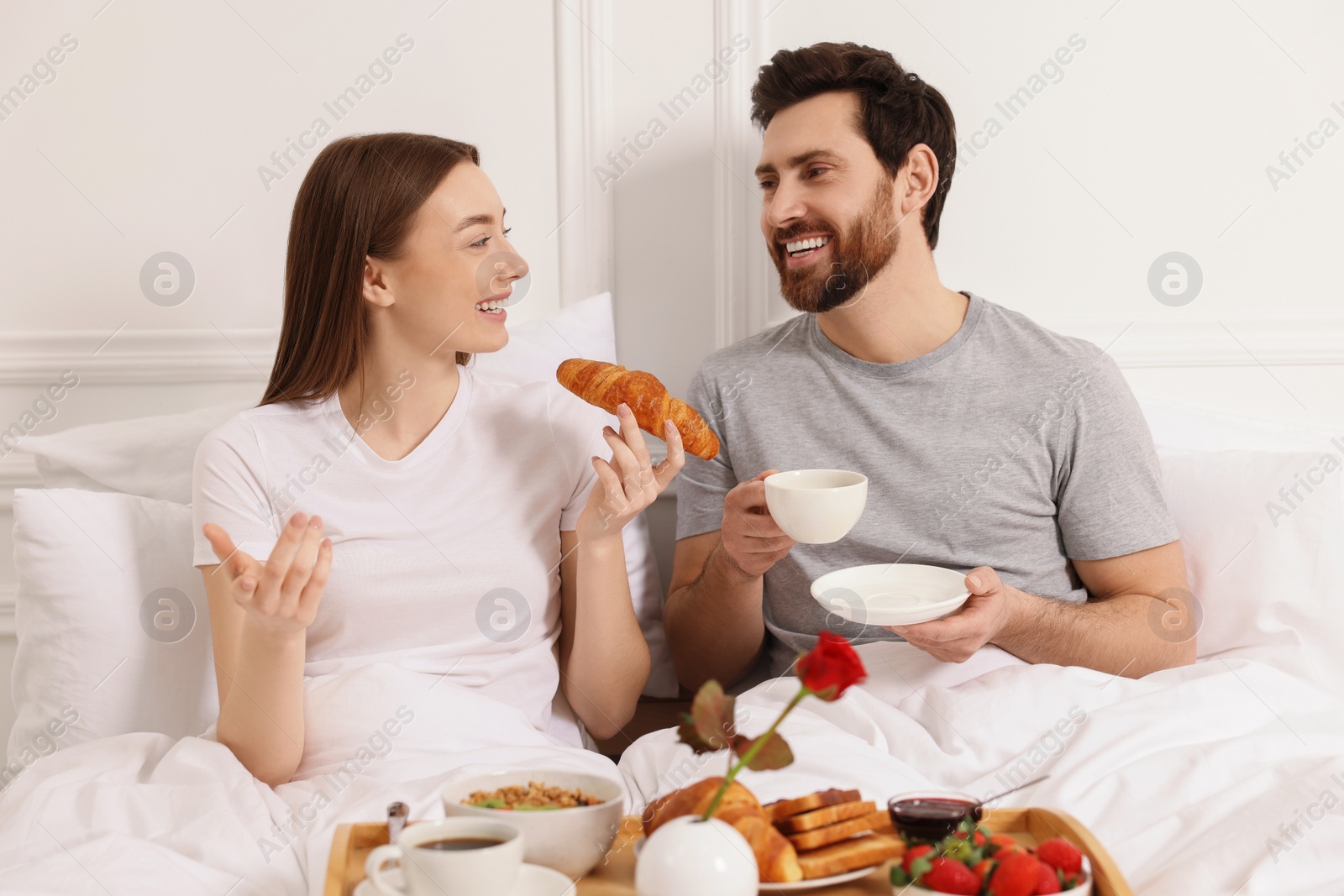 Photo of Happy couple having tasty breakfast in bed at home