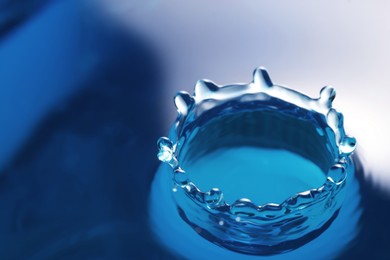 Photo of Splash of clear water with drops on blue background, closeup