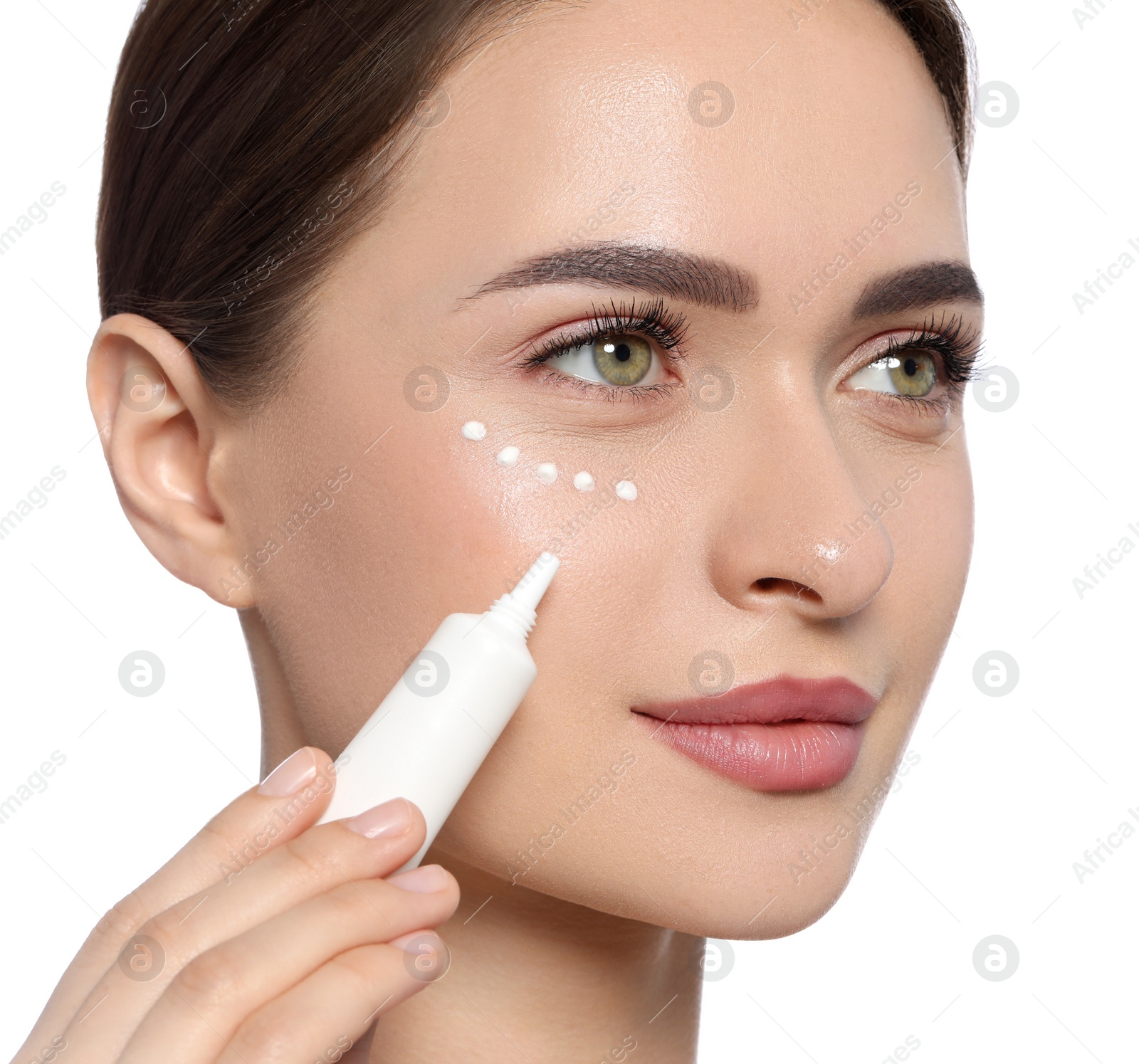 Photo of Young woman applying cream under eye on white background