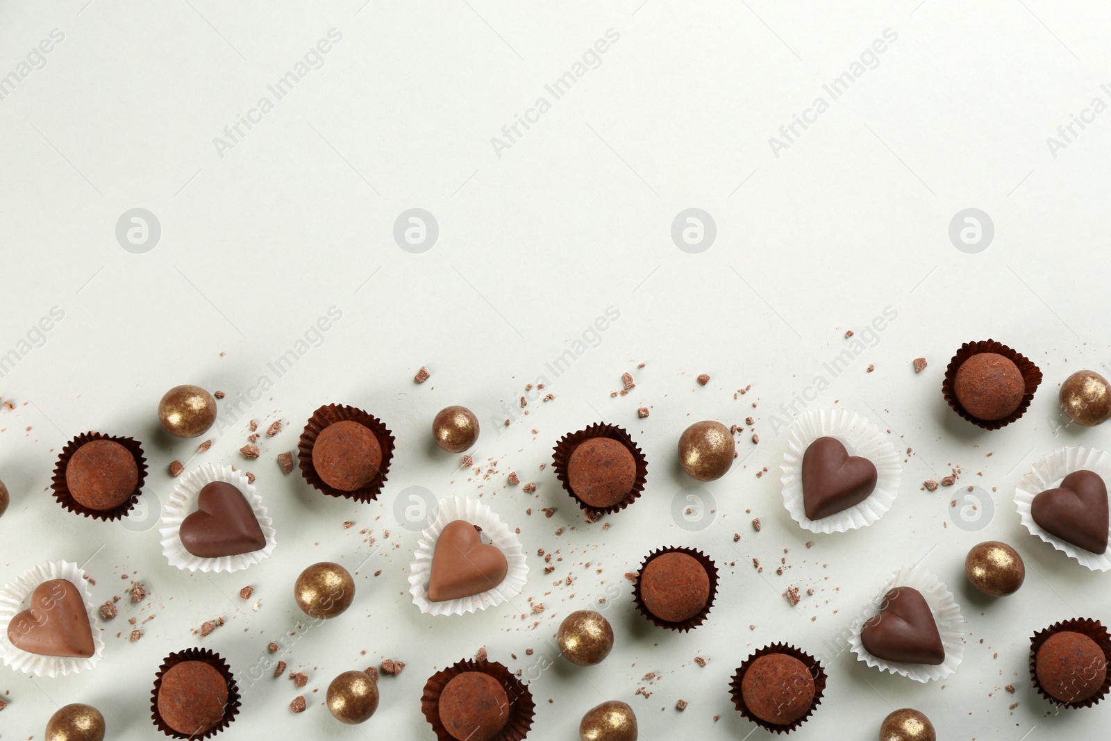 Photo of Different delicious chocolate candies on light background, flat lay. Space for text