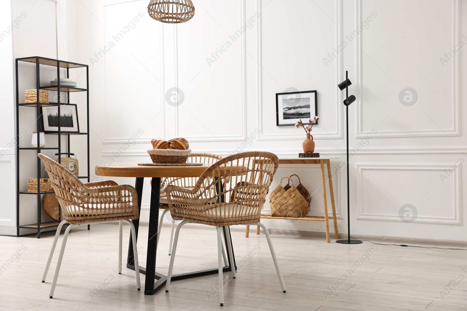 Photo of Dining room interior with wooden table and wicker chairs