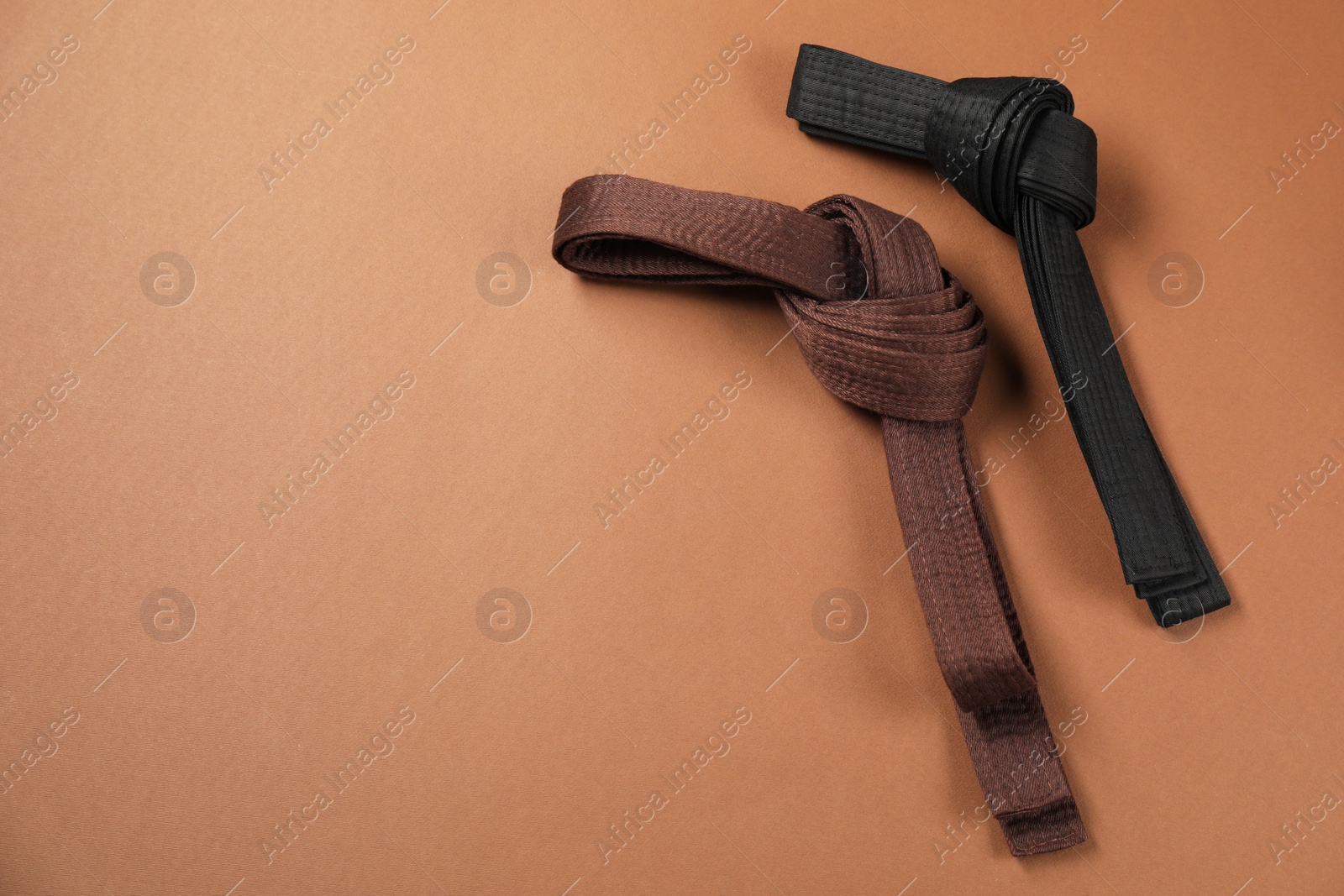 Photo of Karate belts on brown background, flat lay. Space for text