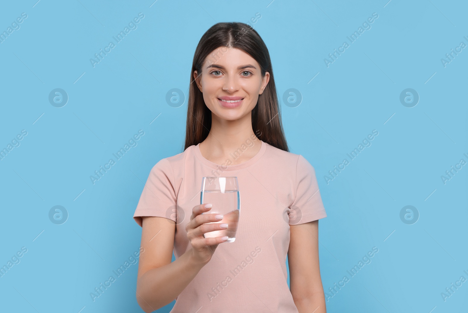Photo of Healthy habit. Portrait of woman holding glass with fresh water on light blue background