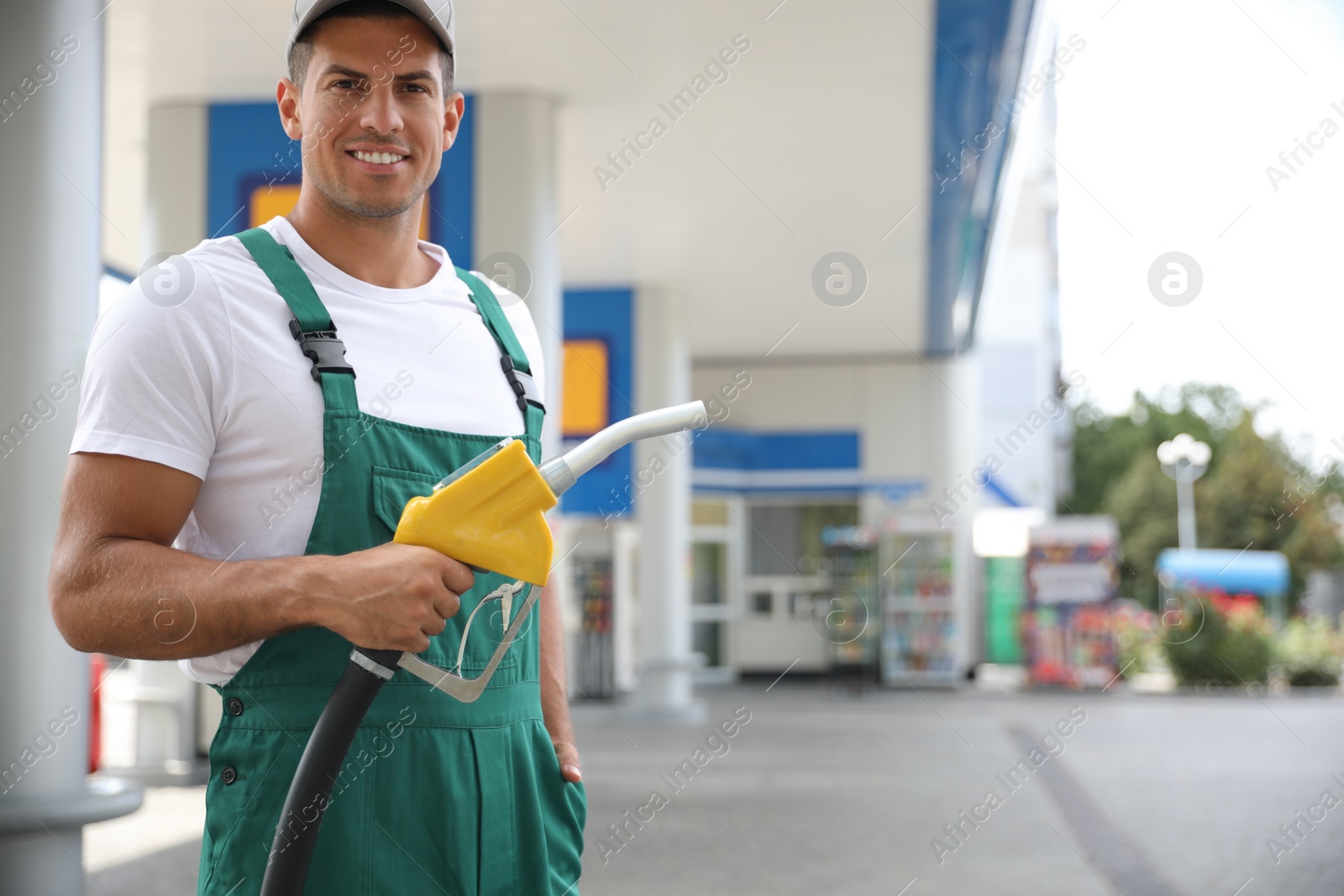 Photo of Worker with fuel pump nozzle at modern gas station