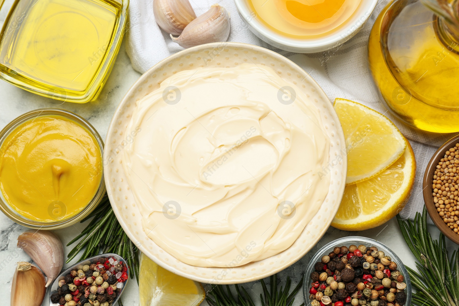 Photo of Bowl with fresh mayonnaise and ingredients on white marble table, flat lay