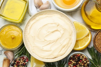 Photo of Bowl with fresh mayonnaise and ingredients on white marble table, flat lay