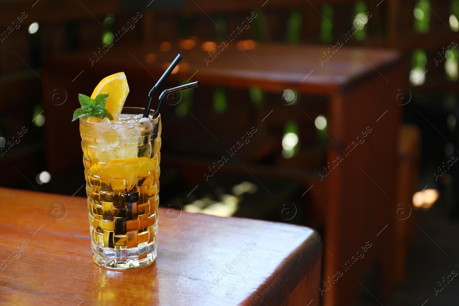 Photo of Glass of delicious cocktail with ice on table in bar