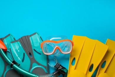 Photo of Different flippers and mask on light blue background, flat lay. Space for text