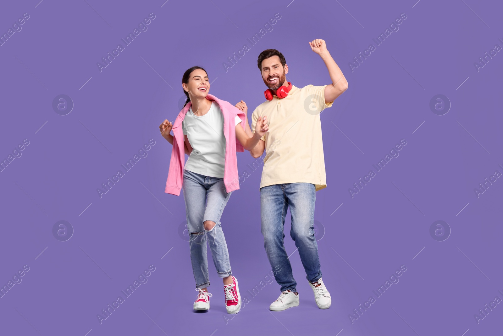 Photo of Happy couple dancing together on violet background