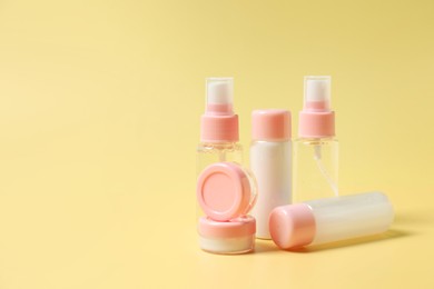 Photo of Cosmetic travel kit. Small containers of personal care products on yellow background, space for text