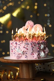 Beautiful birthday cake with burning candles and decor on wooden table