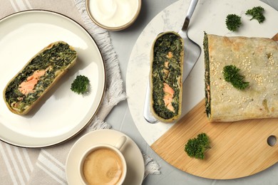 Photo of Delicious strudel with salmon and spinach served on light grey table, flat lay