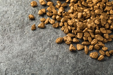 Photo of Pile of gold nuggets on grey table, space for text