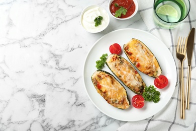 Photo of Baked stuffed zucchinis served with sauces on white marble table, flat lay. Space for text