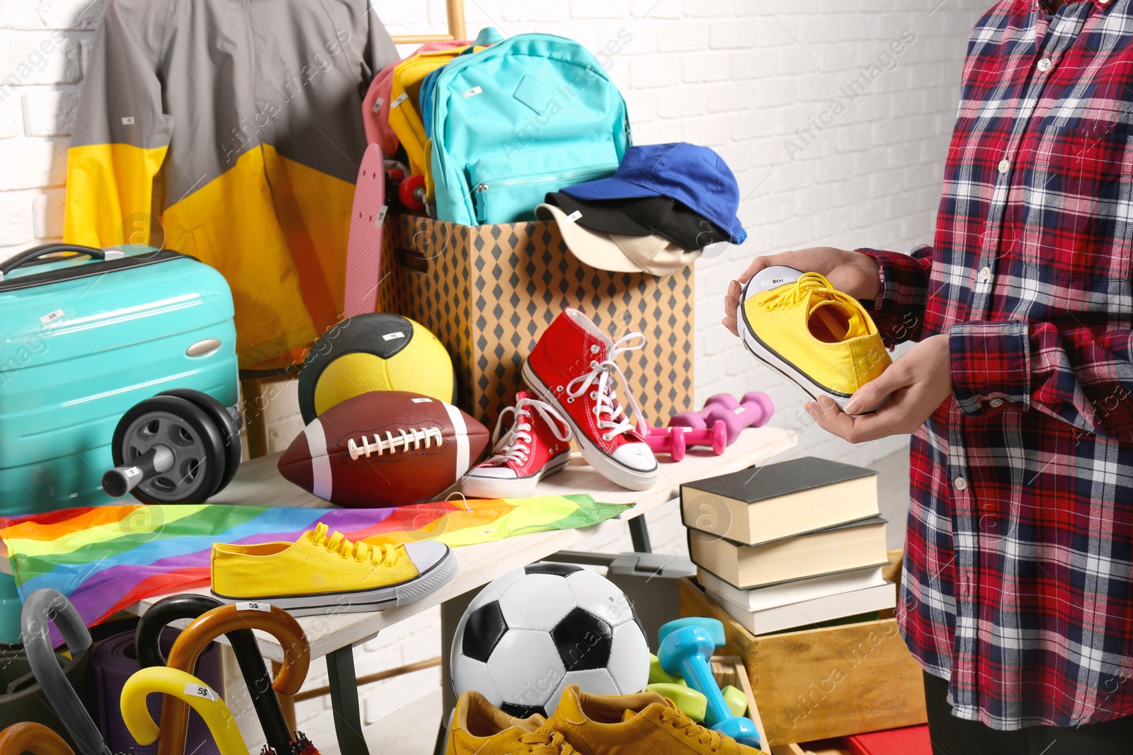 Photo of Woman holding sneaker near many different stuff indoors, closeup. Garage sale