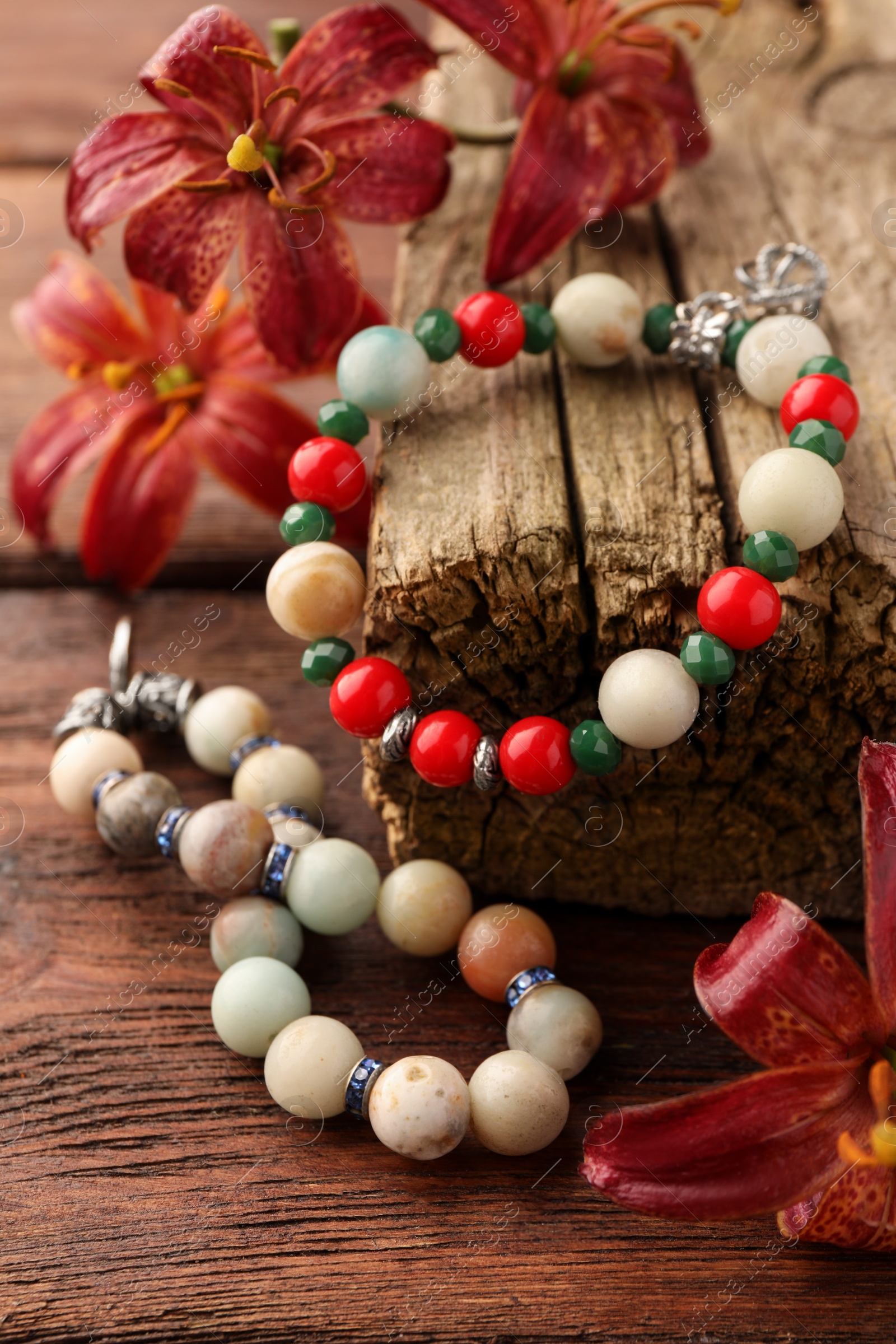 Photo of Stylish presentation of beautiful bracelets with gemstones on wooden table