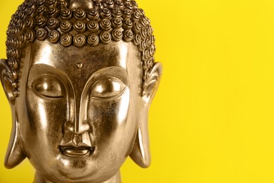 Beautiful golden Buddha sculpture on yellow background, closeup. Space for text