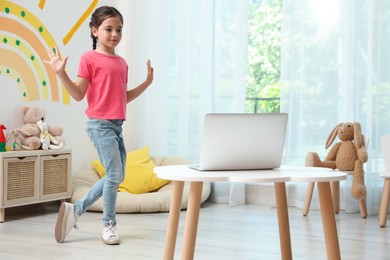 Photo of Cute little girl taking online dance class at home