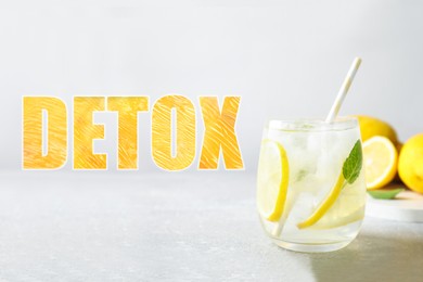 Image of Glass of lemon water on light grey table and word Detox