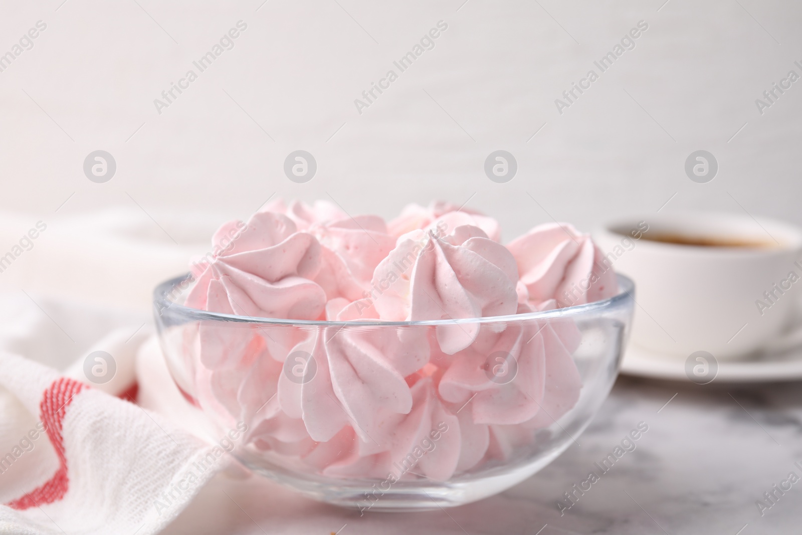 Photo of Tasty meringue cookies in bowl on white marble table