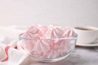 Photo of Tasty meringue cookies in bowl on white marble table