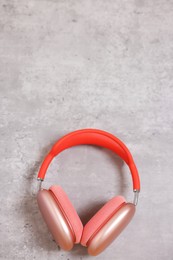 Stylish pink headphones on light grey table, top view. Space for text