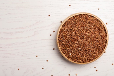 Buckwheat grains on white wooden table, top view. Space for text